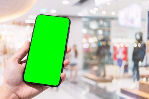 Close-up of female use smartphone blurred images in the mall and Clothes shop blur of the background.