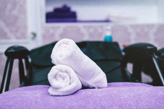 Turquoise spa towels pile on armchairs with washing stands in hairdressing salon.