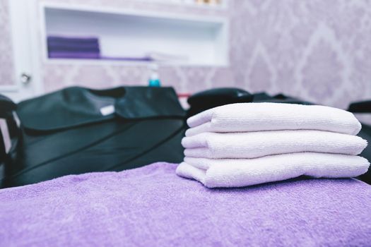 Turquoise spa towels pile on armchairs with washing stands in hairdressing salon.