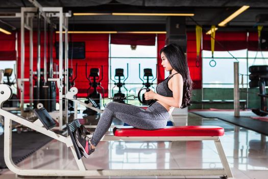 Fitness Asian women performing doing exercises training with rowing machine (Seat Cable Rows Machine) in sport gym interior and fitness health club with sports exercise equipment Gym background.