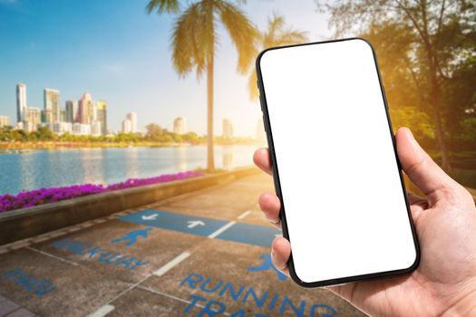 Close-up of female use smartphone blurred images in road pathway in the park for relaxing walking jogging or ride bicycle and exercise at Cityscape blur of the background.