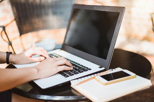 Business Asian woman working with laptop computer and smartphone on office outdoor.