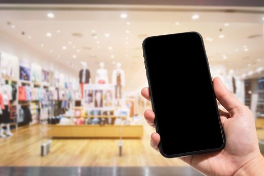 Close-up of female use smartphone blurred images in the mall and Clothes shop blur of the background.