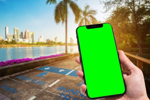 Close-up of female use smartphone blurred images in road pathway in the park for relaxing walking jogging or ride bicycle and exercise at Cityscape blur of the background.