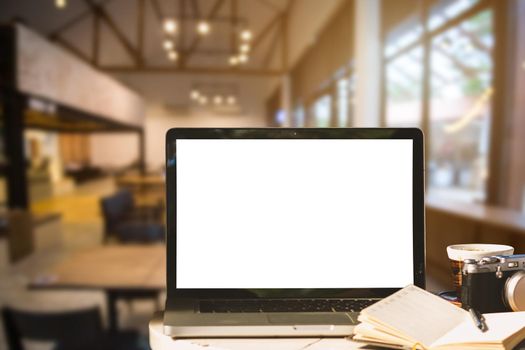 Mockup image of laptop with blank white screen with camera,notebook,coffee cup on wooden table of In the coffee shop background.