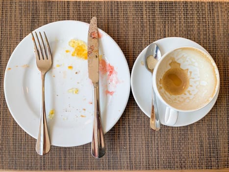 empty white dishes and coffee cup with after breakfast on wooden table.