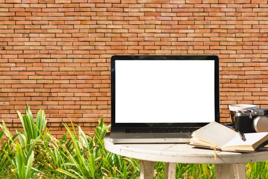 Mockup image of laptop with blank black screen with camera,notebook,coffee cup on wooden table with wall large texture background.