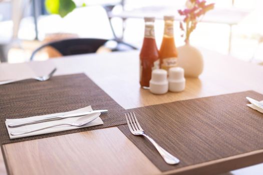 Close-up of luxurious spoon and fork, flower vaseson, sauce bottle the dining table decoration in hotel