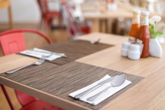 Close-up of luxurious spoon and fork, flower vaseson, sauce bottle the dining table decoration in hotel