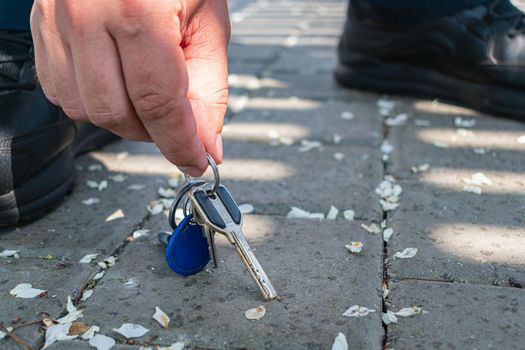 A passer-by picks up a bunch of keys lost by someone on the sidewalk
