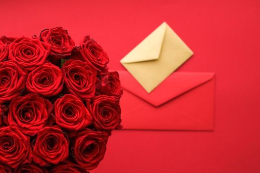 Holiday gift, flowers flatlay and happy relationship concept - Love letter and flower delivery service on Valentines Day, luxury bouquet of red roses and card envelopes on red background