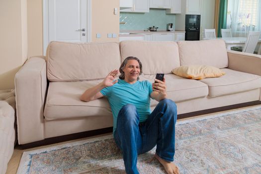 An adult man on the phone talking on video in an apartment.