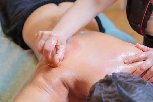 A hijama master performs a back massage with a vacuum can. Close-up
