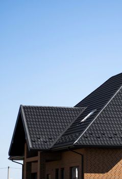 Brown corrugated metal profile roof installed on a modern house. The roof of corrugated sheet. Roofing of metal profile wavy shape. Modern roof made of metal. Metal roofing