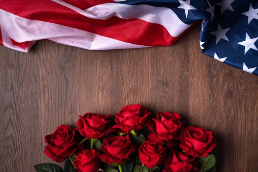Concept of U.S. Independence day or Memorial day. National flag and red rose over dark wooden table background.