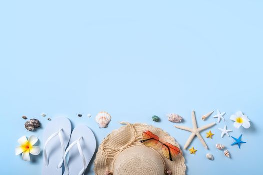 Summer beach background design concept. Top view of holiday travel with shells, hat, slipper on blue background.