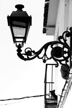Whitewashed facade with balcony and dog in Altea village, Alicante, Spain. Vintage Streetlight in the foreground