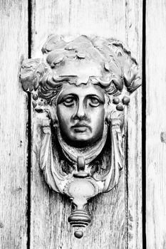 Vintage door knocker face shape on brown wooden door in Altea, Alicante, Spain