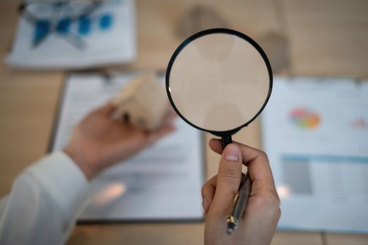 A woman holding magnifying glass and checking house model .Real Estate House Appraisal And Inspection concept