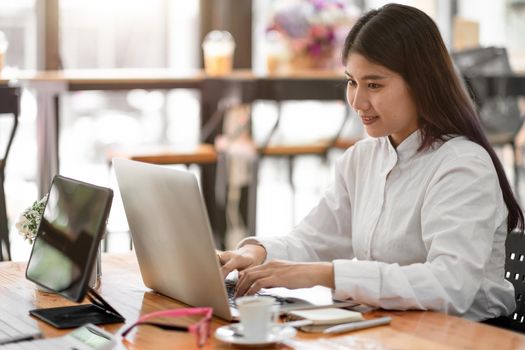 Charming asian businesswoman sitting working on laptop in office.