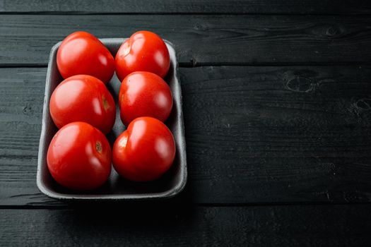 Red tomatoes, on black wooden table with copy space for text