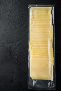 Slices of yellow cheese, sealed pack, on black background with copy space for text