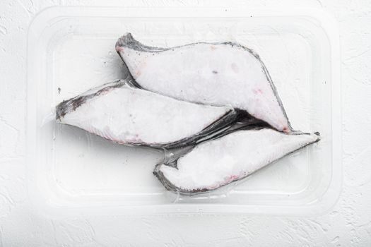 Frozen Greenland halibut steaks vacuum pack set, on white stone table background, top view flat lay