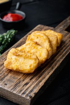 Homemade chicken nuggets fried on black wooden table.