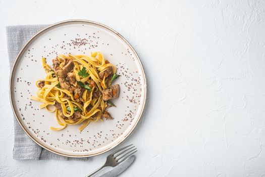 Rabbit stew tagliatelle set, on plate, on white stone background, top view flat lay, with copy space for text