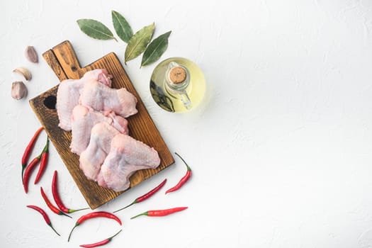 Uncooked chicken wings with spices set, on wooden cutting board, on white background, top view flat lay, with copy space for text
