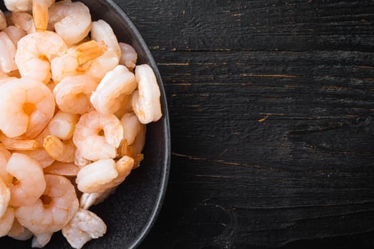 Boiled Peeled Shrimps, Prawns set, in bowl, on black wooden table, top view flat lay, with copy space for text