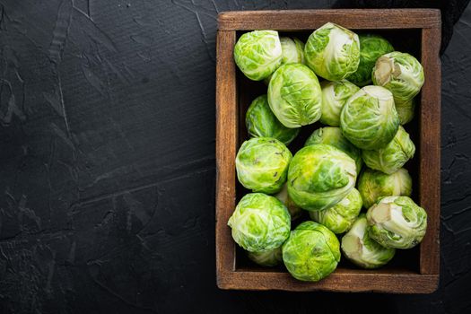 Raw brussels sprouts, on black textured background, flat lay with space for text
