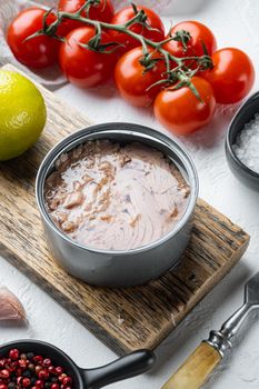 Canned Wild Yellowfin Tuna set, on wooden cutting board, on white background with herbs and ingredients