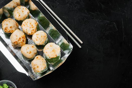 Take away sushi rolls in containers, philadelphia rolls and baked prawn rolls set, on black stone background , with copyspace and space for text