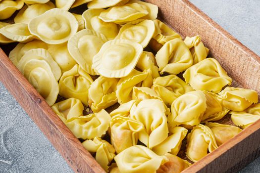 Italian raw handmade Tortellini and Ravioli set, in wooden box, on gray background