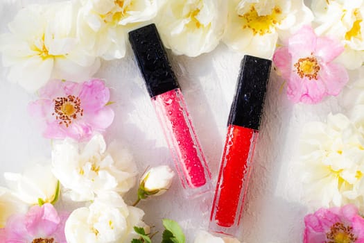 Lip gloss and rose. Lipstick. Beautiful lips. Decorative cosmetics . Well-groomed face. Makeup. Cosmetics without labels. Flowers