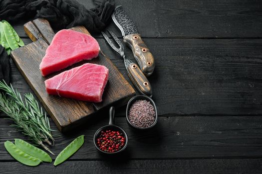 Raw tuna steak, fresh red tuna fillet with ingredients, green pea, sesame and spices set, on wooden cutting board, on black wooden background , with copyspace and space for text