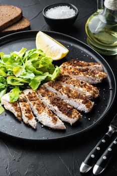 Crumbed, chicken breast fillet grilled, on black background