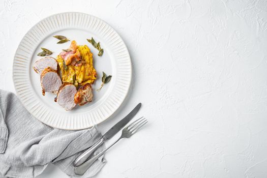 Grilled pork fillet and mash potatoe gratin with sage and prosciutto set, on plate dish, on white stone background, top view flat lay , with copyspace and space for text