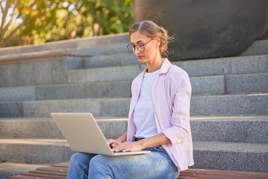 Businesswoman sitting stairs summer park using laptop Business persone working remote. Outdoor Successful european caucasian woman freelancer make video call teacher study work online lessons