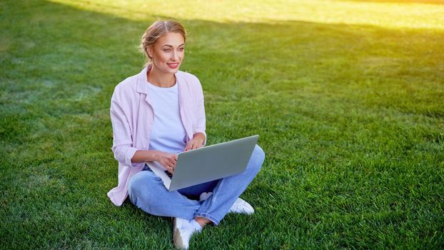 Businesswoman sitting grass summer park using laptop Business persone working remote. Outdoors Successful european caucasian woman freelancer make video call teacher study work online lessons