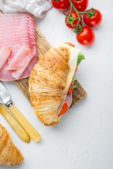 French food for breakfast. Baked Croissant sandwich with ham greens and cheese set, with herbs and ingredients, on white stone background, top view flat lay, with copy space for text