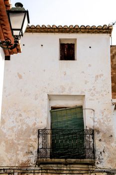Old house facade with rusty balcony and green blind in Altea, Alicante, Spain