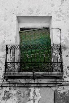 Old house facade with rusty balcony and green blind in Altea, Alicante, Spain