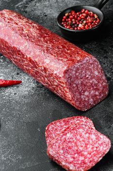 Dry salami sausage with fresh rosemary and spices set, on black dark stone table background