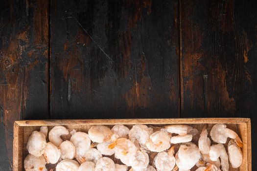 Frozen peeled boiled prawns set, in wooden box, on old dark wooden table, top view flat lay, with copy space for text