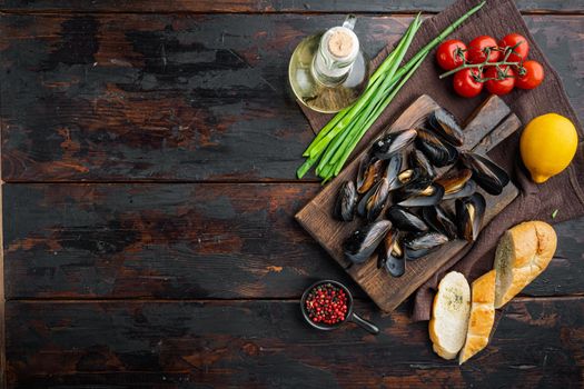 Steamed mussels in white wine set, on wooden cutting board, on old dark wooden table background, top view flat lay , with copyspace and space for text