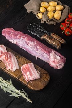 Organic pork fillet with ingredients and herbs for grill or baking, sage, potatoe set, on black wooden table background