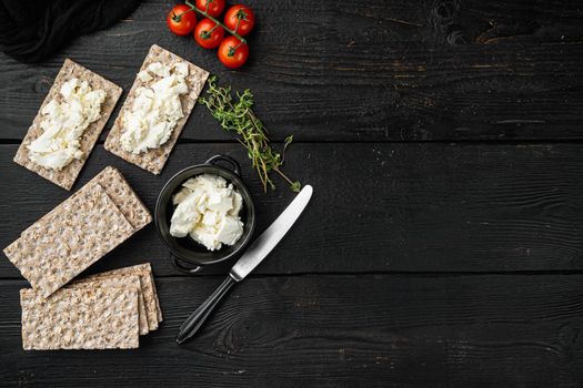 Crisp breads with butter set, on black wooden table background, top view flat lay, with copy space for text