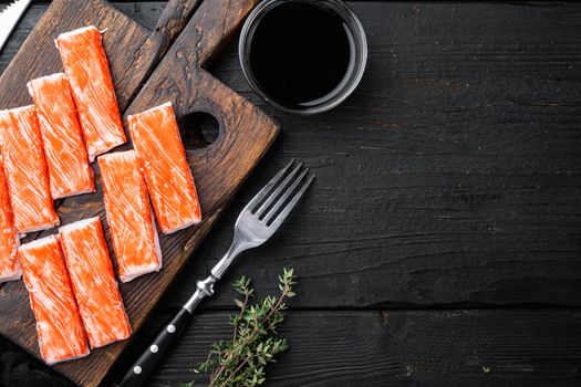Asian snack surimi set, on wooden cutting board, on black wooden table background, top view flat lay , with copyspace and space for text